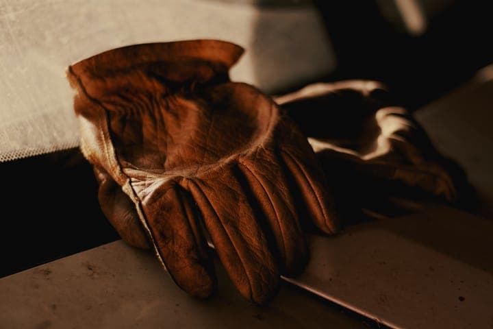 A pair of worn leather work gloves in low, warm light