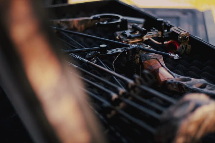 A compound bow and arrows in an open case in the bed of a truck